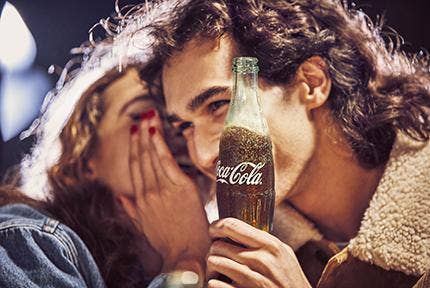 boy and girl gossiping with a coke bottle